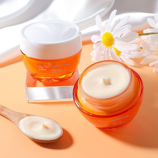 Two jars of cream with a spoonful of cream and daisies on a peach background