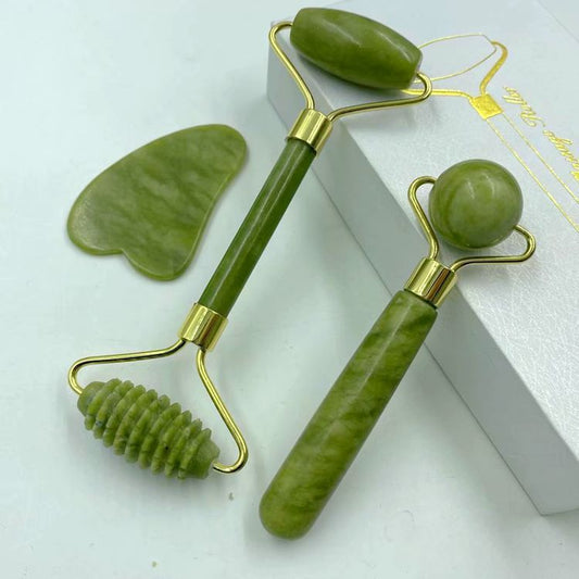 Green facial roller and massage tool set on a white background