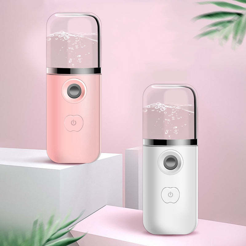 Two portable humidifiers, one pink and one white, on a light pink background with green leaves.