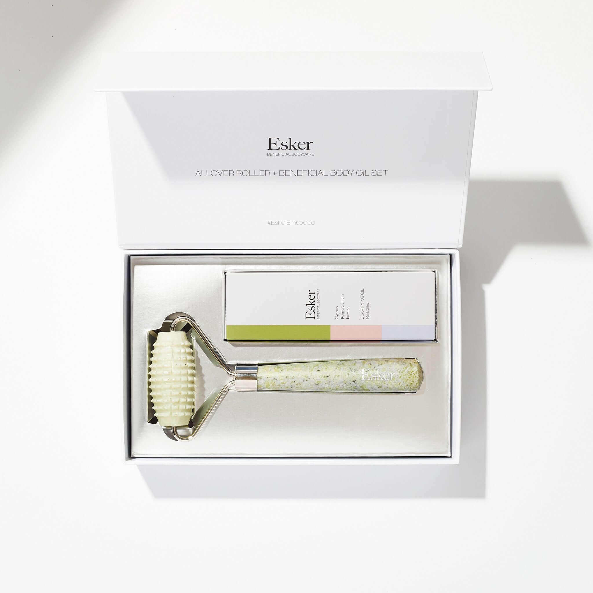 Esker jade roller and body oil set in a white gift box on a light gray background