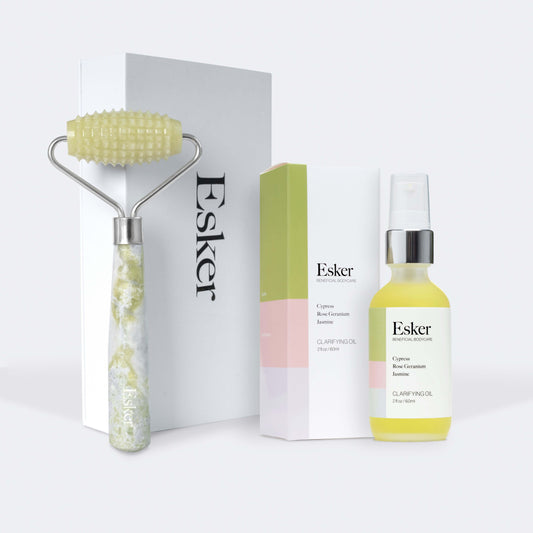 Esker skincare product set including a roller, box, and bottle of clarifying oil on a white background