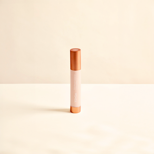 Cosmetic concealer stick from YENSA with rose gold cap and body on a beige background